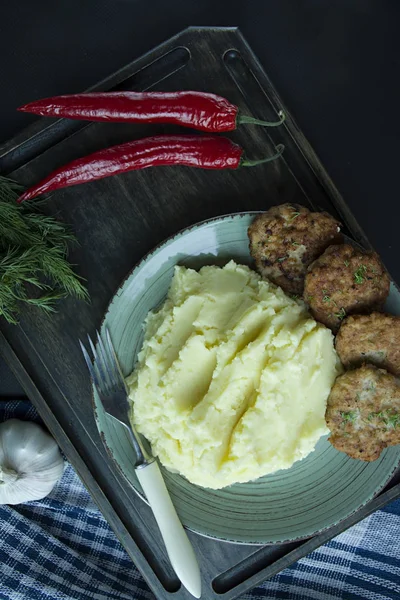 Costeletas de porco com purê de batatas, verdes e legumes frescos em um fundo preto. Vista de cima . — Fotografia de Stock