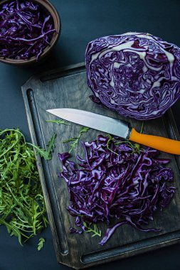 Kırmızı lahana ile roket bir siyah arka plan üzerine dilimlenmiş. Vejetaryen sağlıklı yiyecekler. Doğru beslenme. Yukarıdan görüntülemek