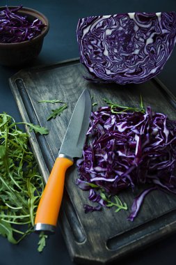 Kırmızı lahana ile roket bir siyah arka plan üzerine dilimlenmiş. Vejetaryen sağlıklı yiyecekler. Doğru beslenme. Yukarıdan görüntülemek