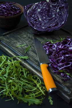 Kırmızı lahana ile roket bir siyah arka plan üzerine dilimlenmiş. Vejetaryen sağlıklı yiyecekler. Doğru beslenme. Yukarıdan görüntülemek