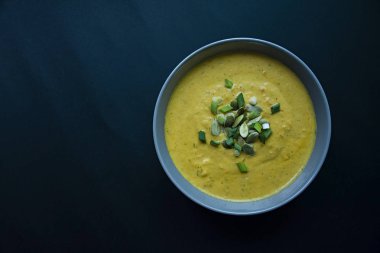 Krem ve kabak çekirdeği, kabak çorbası servis hafif bir kapta, üstten görünüm. Doğru ve sağlıklı gıda. Siyah arka plan.