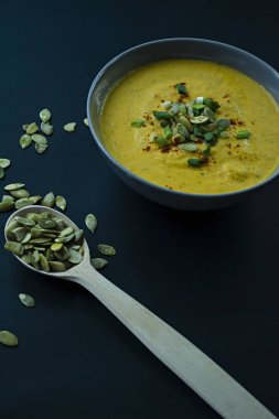 Krem ve kabak çekirdeği, kabak çorbası servis hafif bir kapta, üstten görünüm. Doğru ve sağlıklı gıda. Siyah arka plan.