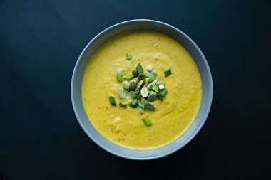 Krem ve kabak çekirdeği, kabak çorbası servis hafif bir kapta, üstten görünüm. Doğru ve sağlıklı gıda. Siyah arka plan.