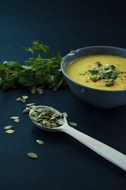 Krem ve kabak çekirdeği, kabak çorbası servis hafif bir kapta, üstten görünüm. Doğru ve sağlıklı gıda. Siyah arka plan.