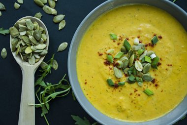 Krem ve kabak çekirdeği, kabak çorbası servis hafif bir kapta, üstten görünüm. Doğru ve sağlıklı gıda. Siyah arka plan.