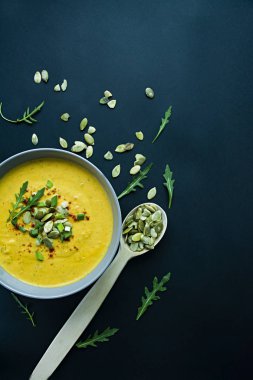Krem ve kabak çekirdeği, kabak çorbası servis hafif bir kapta, üstten görünüm. Doğru ve sağlıklı gıda. Siyah arka plan.