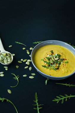 Krem ve kabak çekirdeği, kabak çorbası servis hafif bir kapta, üstten görünüm. Doğru ve sağlıklı gıda. Siyah arka plan.