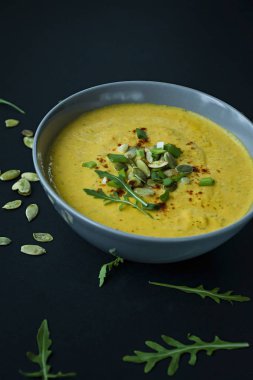 Krem ve kabak çekirdeği, kabak çorbası servis hafif bir kapta, üstten görünüm. Doğru ve sağlıklı gıda. Siyah arka plan.