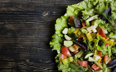 Taze salatalık, domates, tatlı biber, marul, kırmızı soğan, beyaz peynir ve zeytin ile zeytinyağı koyu ahşap arka plan üzerinde Yunan salatası.