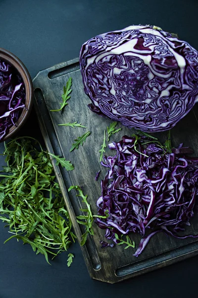 Red cabbage sliced with rocket on a black background. Vegetarian healthy food. Proper nutrition. View from above