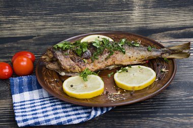 Fırında balık, kızarmış sebze ve limonla servis ediliyor. Üst görünüm.