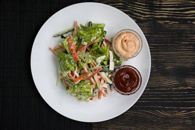 Diyet gıda, imitasyon yengeç sopa, soya sosu ve Japon susam ile taze sebze salatası. Şeritler halinde kesin. Koyu ahşap arka plan. Yukarıdan görüntülemek.