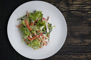Diyet gıda, imitasyon yengeç sopa, soya sosu ve Japon susam ile taze sebze salatası. Şeritler halinde kesin. Koyu ahşap arka plan. Yukarıdan görüntülemek.
