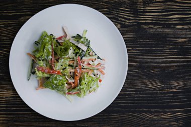 Diyet gıda, imitasyon yengeç sopa, soya sosu ve Japon susam ile taze sebze salatası. Şeritler halinde kesin. Koyu ahşap arka plan. Yukarıdan görüntülemek.