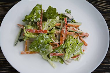 Diyet gıda, imitasyon yengeç sopa, soya sosu ve Japon susam ile taze sebze salatası. Şeritler halinde kesin. Koyu ahşap arka plan. Yukarıdan görüntülemek.