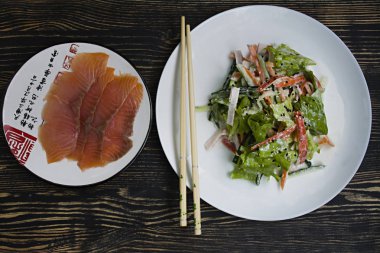 Diyet gıda, imitasyon yengeç sopa, karides, soya sosu ve Japon susam terbiyeli parçaları ile taze sebze salatası. Şeritler halinde kesin. Koyu ahşap arka plan. Yukarıdan görüntülemek.