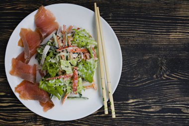 Diyet gıda, imitasyon yengeç sopa, parça et, ekşi krema ve Japon susam ile giyinmiş ile taze sebze salatası. Şeritler halinde kesin. Koyu ahşap arka plan. Yukarıdan görüntülemek