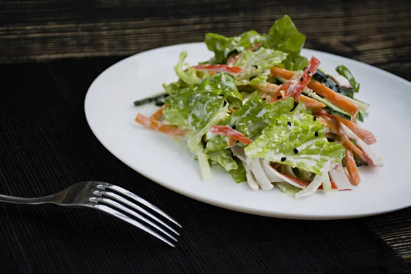 Dieet voedsel, verse fruit salade met imitatie krab stick, gekruid met sojasaus en Japanse sesame. Snijd in reepjes. Donkere houten achtergrond. Van bovenaf bekijken. — Stockfoto
