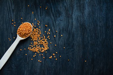 Bir kaşık turuncu mercimek. Koyu ahşap arka plan üzerinde. Yukarıdan görüntüleyin. Uzay kopyalayın. Metin için yer.