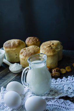 Arka plan Paskalya kek karanlık bir arka plan üzerinde süt ile sürahi. Kurutulmuş meyve ile taze kek. Paskalya kek pişirme süreci. Yandan görüntülemek.