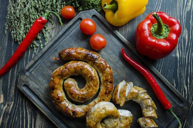 Kızarmış sosis otlar ve Baharatlar, ahşap arka plan ile. Ve ev yapımı sosis pişmiş halka. Bir ahşap tahta Yeşiller ve sebze ile servis. Yukarıdan görüntülemek.