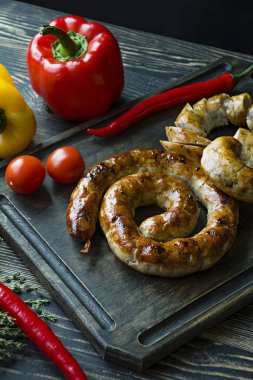 Kızarmış sosis otlar ve Baharatlar, ahşap arka plan ile. Ve ev yapımı sosis pişmiş halka. Bir ahşap tahta Yeşiller ve sebze ile servis. Yan görünüm.