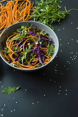 Kırmızı lahana, havuç ve yeşil salata. Dilimlenmiş sebze ve otlar ile dekore edilmiştir. Kesme şeritler. Koyu arka plan.