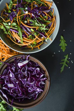 Kırmızı lahana, havuç ve yeşil salata. Dilimlenmiş sebze ve otlar ile dekore edilmiştir. Kesme şeritler. Koyu arka plan.