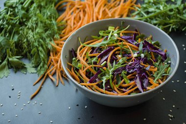 Kırmızı lahana, havuç ve yeşil salata. Dilimlenmiş sebze ve otlar ile dekore edilmiştir. Kesme şeritler. Koyu arka plan.