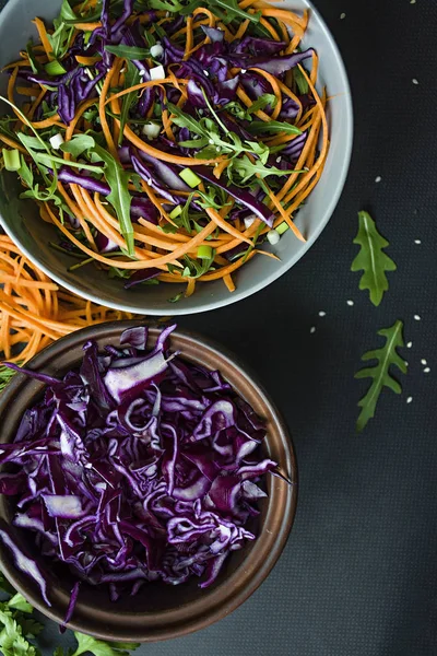 Kırmızı lahana, havuç ve yeşil salata. Dilimlenmiş sebze ve otlar ile dekore edilmiştir. Kesme şeritler. Koyu arka plan.