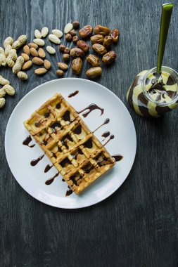 Koyu ahşap arka planda çikolata kaplı geleneksel Belçikalı Waffle 'ları. Lezzetli kahvaltı. Raschlichnymi fındık, somun hamur ile dekore.