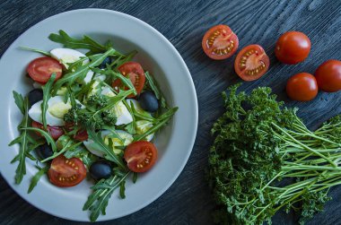 Taze domates, Arugula, yumurta, koyu ahşap arka planda zeytin yağı ile zeytin ile Yunan salatası. Sağlıklı yiyecekler. Veggie çanak.
