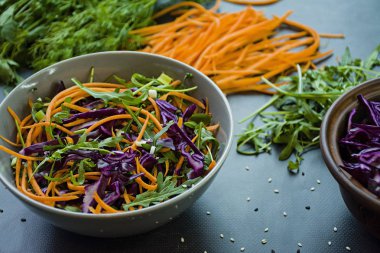 Kırmızı lahana, havuç ve yeşil salata. Dilimlenmiş sebze ve otlar ile dekore edilmiştir. Kesme şeritler. Koyu arka plan.