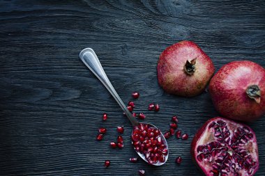 Koyu ahşap arka plan üzerinde sağlıklı taze nar. Bir kaşık taze nar taneleri ile. Canlı odak. Koyu ahşap arka plan. Yukarıdan görüntülemek.