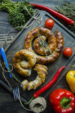 Kızarmış sosis otlar ve Baharatlar, ahşap arka plan ile. Ve ev yapımı sosis pişmiş halka. Ahşap bir gemide bir çatal, otlar ve sebze ile servis. Yukarıdan görüntülemek.