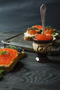 Çömlek içinde kırmızı havyar. Close. Koyu ahşap arka plan.