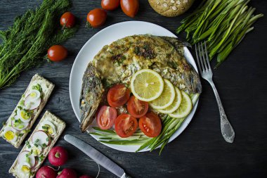 Fırında Pike, sebze ve otlar ile dekore edilmiş. Bir tabak üzerinde hizmet veriyor. Doğru beslenme. Koyu ahşap arka plan.