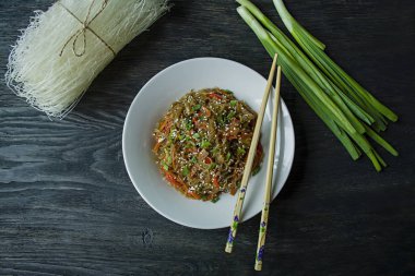Asya mutfağı. Yeşillik ve yengeç çubukları ile süslenmiş sebze ile kızarmış, sellophane erişte salatası. Funchoza mı? Doğru beslenme. Sağlıklı yiyecekler. Yukarıdan görüntüle. Koyu ahşap arka plan.