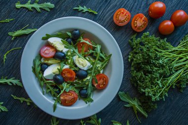 Taze domates, Arugula, yumurta, koyu ahşap arka planda zeytin yağı ile zeytin ile Yunan salatası. Sağlıklı yiyecekler. Veggie çanak.