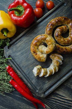 Kızarmış sosis otlar ve Baharatlar, ahşap arka plan ile. Ve ev yapımı sosis pişmiş halka. Bir ahşap tahta Yeşiller ve sebze ile servis. Yan görünüm.