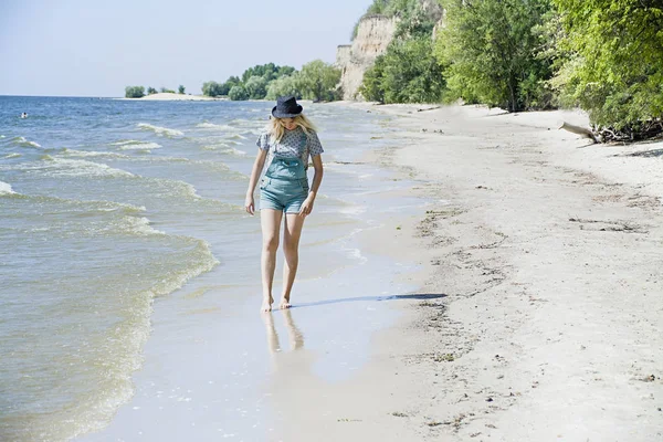 Девушка на пляже в шляпе гуляет по берегу моря, концепция отдыха. Море, пляж, лето. Время расслабиться . — стоковое фото
