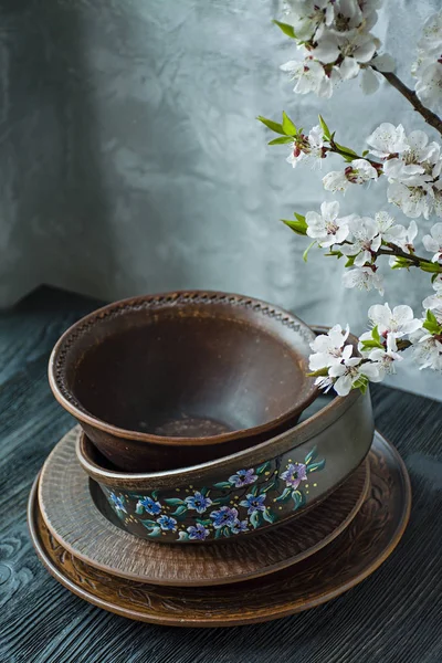 Een set van oude keramische servies. Een set van borden, kommen. Een tak van abrikozen. Donkere houten achtergrond. — Stockfoto