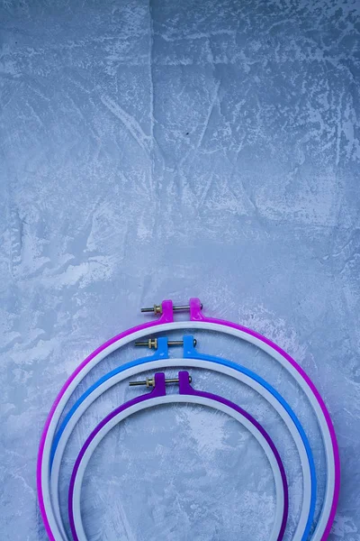 Plastic hoop on a light background under the concrete. Three hoops pink, blue, purple. View from above. Space under the text.