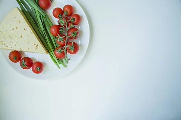 Egy tányér friss sajt, egy ága a friss cseresznye és a zöld fokhagyma. Fehér háttér. Szóköz a szöveghez. — Stock Fotó