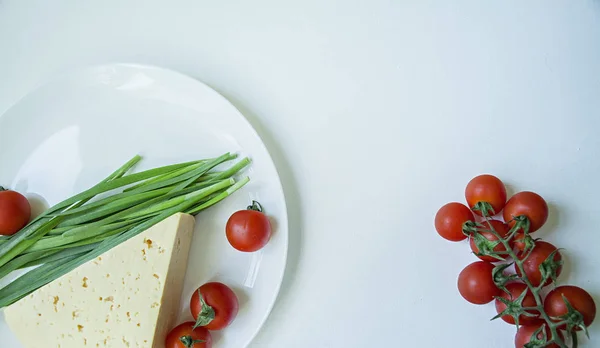 Egy tányér friss sajt, egy ága a friss cseresznye és a zöld fokhagyma. Fehér háttér. Szóköz a szöveghez. — Stock Fotó