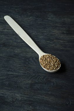 Karabuğday, koyu ahşap bir arka planda ahşap bir kaşık içinde kasık. Yukarıdan görüntüle.