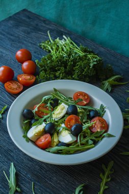 Taze domates, Arugula, yumurta, koyu ahşap arka planda zeytin yağı ile zeytin ile Yunan salatası. Sağlıklı yiyecekler. Veggie çanak.