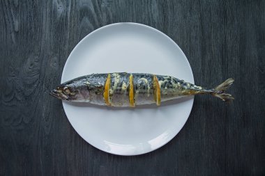 Beyaz bir tabakta limonlu uskumru. Taze sebzeler. Uskumru ızgarası. Yukarıdan görüntüleyin. Ahşap masa.