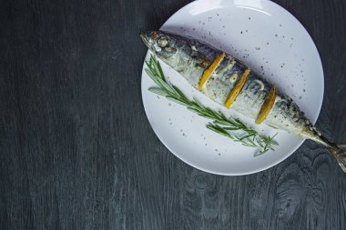 Beyaz bir tabakta limonlu uskumru. Taze sebzeler. Uskumru ızgarası. Yukarıdan görüntüleyin. Tahta masa. Metin için alan.