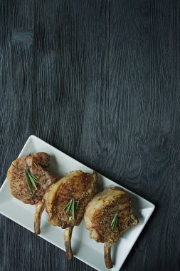 Baharat ve otlar ile domuz kaburga ızgara biftekler. Koyu ahşap arka plan üzerinde görüntüleyin. Metin alanı.